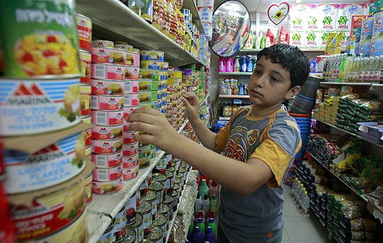 Palestino procura por mercadorias em supermercado da faixa de Gaza; bloqueio j dura trs anos