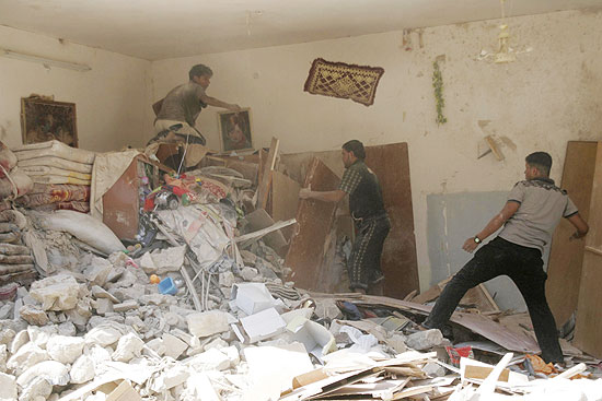 Moradores fazem busca por destroos de uma casa destruda por uma bomba em Ramadi; ataques mataram ao menos sete