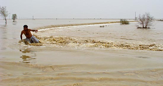 Paquistanês tenta chegar a sua vila após enchente causada por forte chuva de monção em Bakhtiarabad