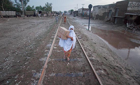 Mulher carrega ajuda humanitria, distribuda pelo Exrcito, em rea atingida por enchentes no norte do Paquisto