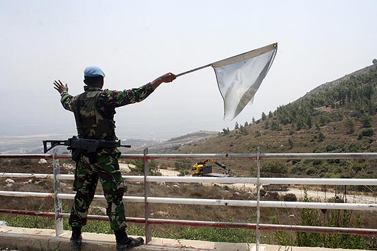 Soldado de paz da ONU agita bandeira branca na fronteira entre Lbano e Israel; troca de tiros matou cinco