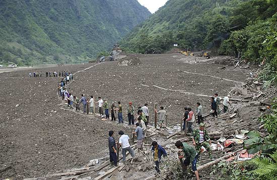 Pessoas usam tbuas para abrir trilha em vila soterrada por deslizamentos na China; mortos j so 1.287