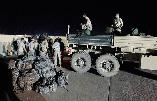 Soldados ajudam a última brigada de combate a embarcar suas malas antes de deixar o Iraque para o Kuait