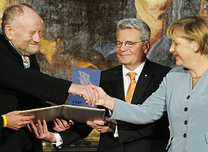 Cartunista dinamarquês Kurt Westergaard ao lado da chanceler alemã Angela Merkel; após polêmica, ele é premiado