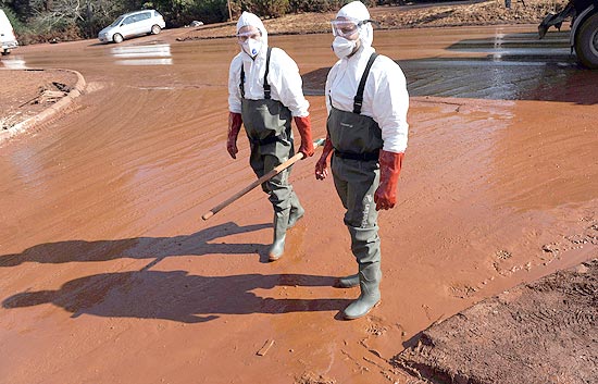 Trabalhadores do resgate atuam em rua coberta de lama em Devecser; dique para deter lama deve ficar pronto amanh