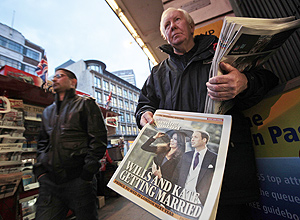 Um homem distribui cpias de um jornal grtis que mostra na capa a notcia do noivado entre o prncipe William e Kate Middleton