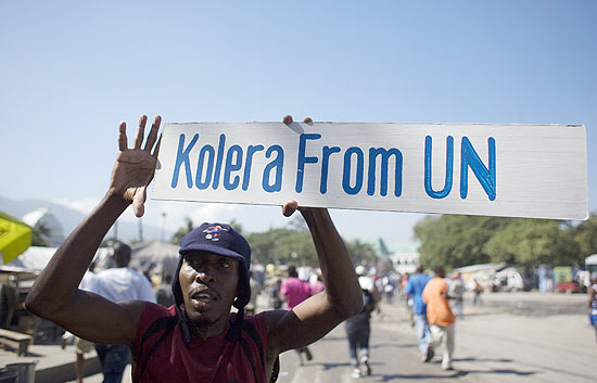 Manifestante segura faixa em que acusa os membros da misso de paz da ONU de terem levado o clera ao Haiti