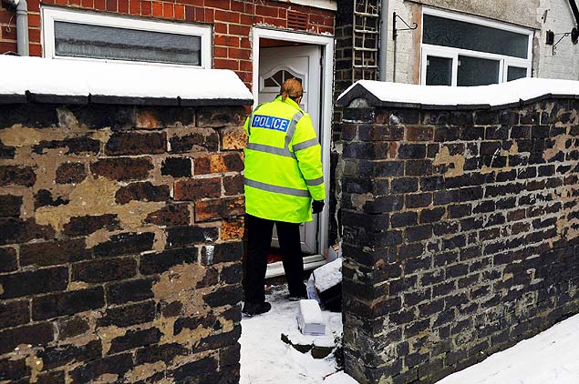 Policial atravessa sobre caixas de siringas ao entrar em um imvel vasculhado em uma operao antiterrorismo no Reino Unido