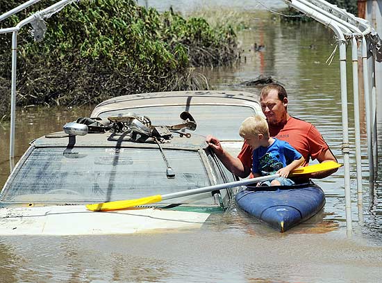 Morador Scott Wogandt e eu filho, Mitchell Kayak, em rua inundada de Bundaberg; enchentes j afetam 200 mil