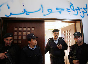 Policiais palestinos na entrada da Al Jazeera em Ramallah, onde foi pichado: "Al Jazeera  uma espi"
