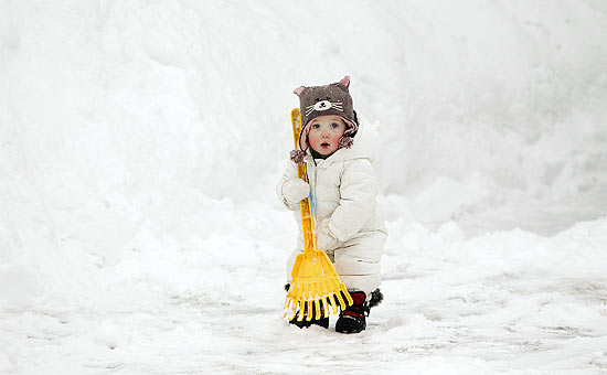 Menina ajuda a mãe a retirar excesso de neve em Cohassett (Massachussetts); neve causa cancelamento de voos nos EUA