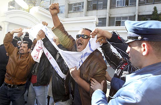 Policial tenta conter manifestante durante protestos em frente ao Ministrio do Trabalho em Argel