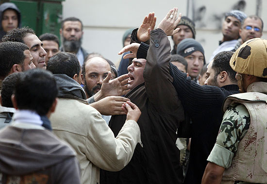 Funcionrio pblico (centro) discute com manifestantes que o impediam de chegar ao principal prdio do governo no Cairo