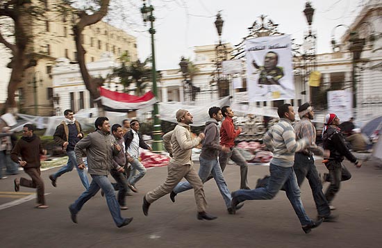 Manifestantes antigoverno correm por rua como parte do exerccio dirio aps passar a noite na praa Tahrir
