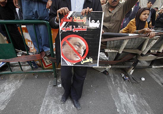 Manifestante segura cartaz com rosto do ditador Hosni Mubarak em frente ao Parlamento egpcio, no Cairo