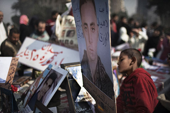 Egpcios que ainda continuam na praa Tahrir seguram fotos dos que morreram durante protestos antigoverno