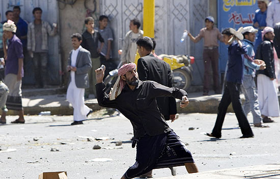 Manifestante antigoverno joga pedras contra partidrios do regime durante enfrentamento em Sanaa