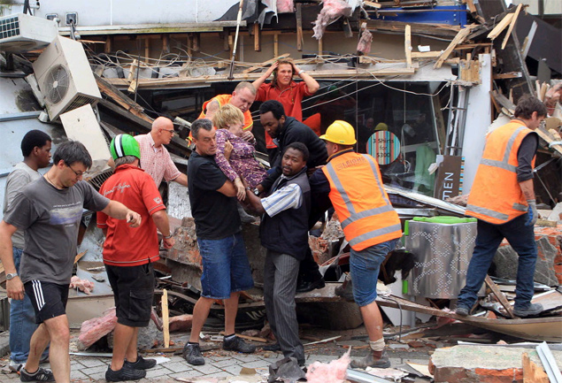 Mulher  retirada de destroos em Christchurch; equipes trabalharo durante a noite em busca de cem soterrados