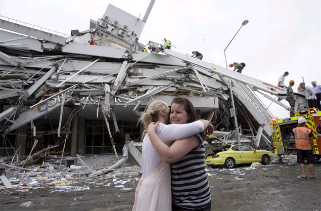 Mulheres se abraam diante de prdio que desmoronou com tremor de magnitude 6,3 em Christchurch; veja galeria