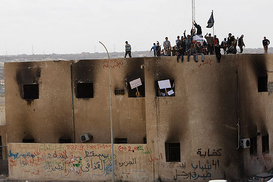 Manifestantes se reunem no topo de uma delegacia de polcia incendiada em Tobruk; cerco apertado em torno de Gaddafi