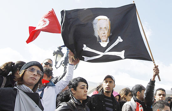 Tunisianos pedem renncia de governo de transio com bandeira retratando o premi Mohamed Ghannouchi
