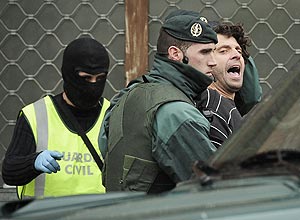 Daniel Pastor ( esq.), um suposto membro do grupo separatista basco ETA,  levado preso por um guarda civil