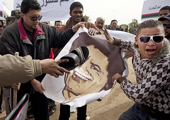Manifestantes antigoverno carregam poster com imagem de Gaddafi; rebeldes reagem a ofensiva no leste