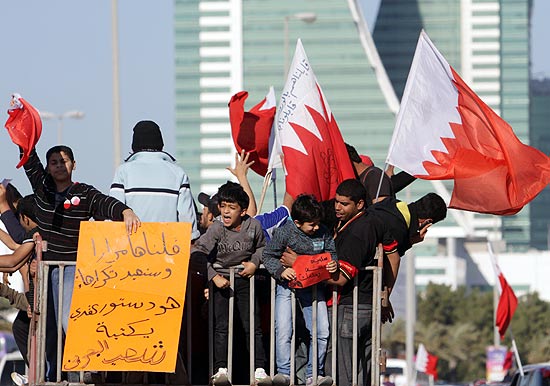 Manifestantes antirregime empunham bandeiras do Bahrein em cima de um caminho na capital, Manama
