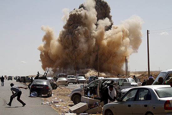 Rebeldes lbios se protegem quando bomba  lanado por avio das foras de Gaddafi nos arredores de Ras Lanuf