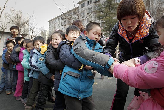 Crianças chinesas brincam de cabo de guerra em Pequim; país quer incentivar segundo filho, mas proibir terceiro