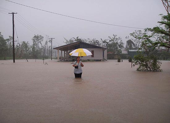 Mulher caminha por rua inundada durante as fortes chuvas dos ltimos dias em Cardwell