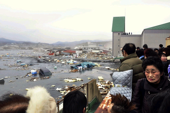 Pessoas olham os danos causados pelo tsunami que atingiu Kesennuma, no norte do Jap&atilde;o
