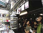 Turistas japoneses veem notícias em banca de jornal