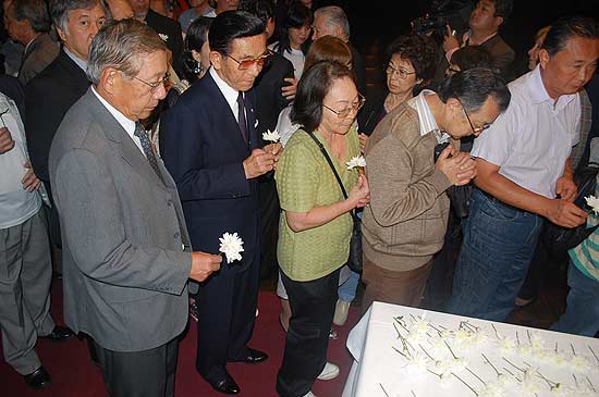 Participantes de cerimnia depositam crisntemos em mesa e oram no auditrio da associao Bunkyo.