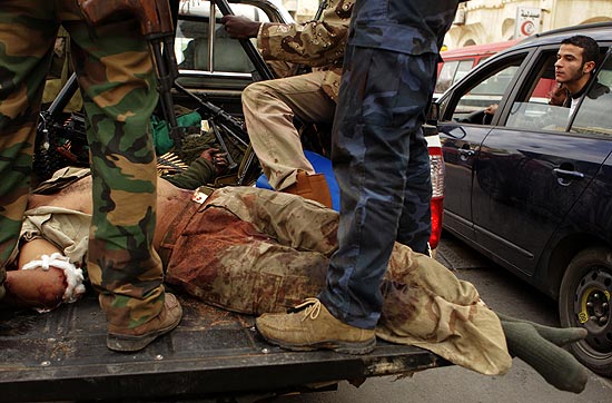 Rebeldes desfilam no centro de Benghazi, no leste, com membro das foras leais a Gaddafi ferido