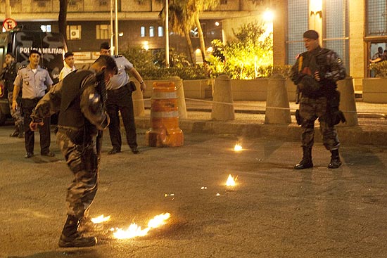 Policial da tropa de choque apaga restos de um artefato após confronto com manifestantes no Rio 