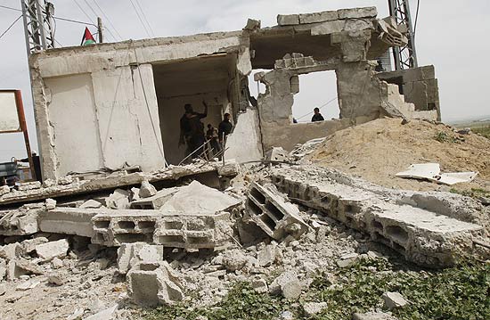 Foras palestinas inspecionam casa destruda por ataque israelense; represlia ao lanamento de 50 foguetes