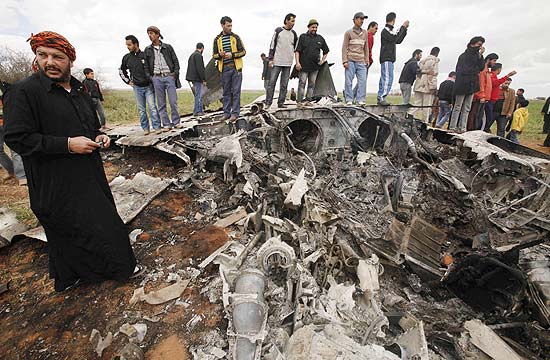 Curiosos olham destroços que seriam do Air Force F-15E perto de Benghazi; os dois pilotos se ejetaram e estão bem