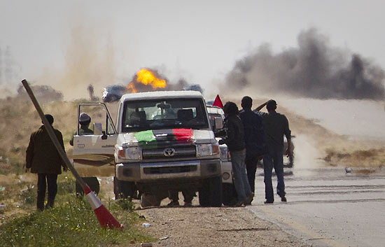 Rebeldes líbios param em estrada e observam morteiros das forças de Gaddafi a alguns quilômetros