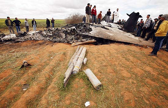 Curiosos observam destroços de avião dos EUA que caiu na Líbia; os dois pilotos se ejetaram e estão bem