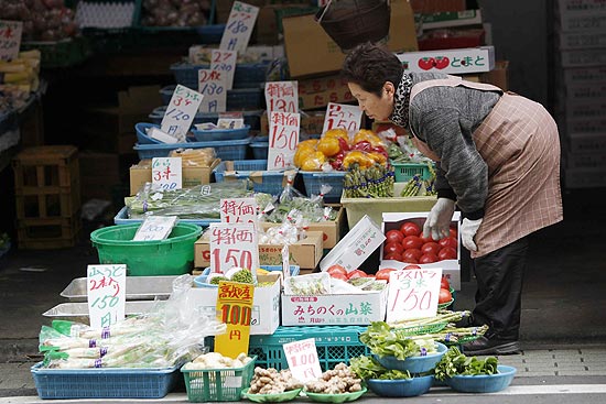 Vendedora confere vegetais em sua loja em Togoshi Ginza, na capital Tquio; gua mineral j est em falta no mercado