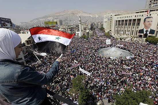 Manifestante pr-Assad agita bandeira sria em ato em Damasco; presidente aceitou a renncia de seu gabinete