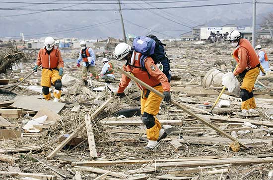 Bombeiros buscam entre escombros do povoado de Ishinomaki, em Miyagi; radiao atrasa recuperao de corpos em Fukushima