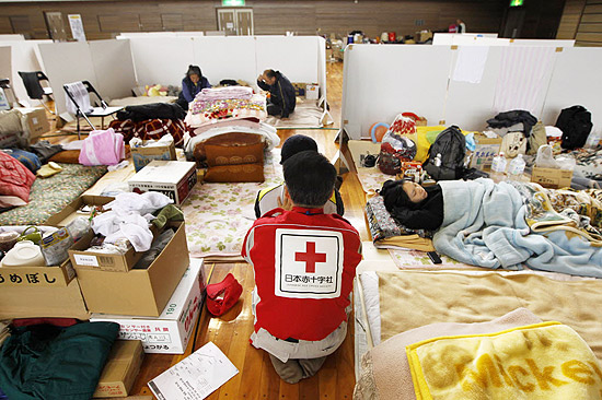 Em Fukushima, um membro da Cruz Vermelha orienta um dos prejudicados por causa da catástrofe natural que atingiu o Japão