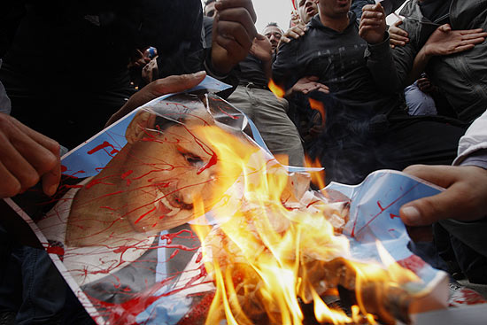 Manifestante queima imagem do ditador Bashar al Assad em protestos em frente à Embaixada da Síria no Chipre