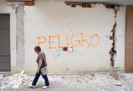 Mulher passa por muro danificado após tremor que atingiu Lorca (Espanha); quase todos os imóveis foram afetados