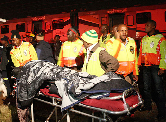 Equipe de resgate leva um dos passageiros feridos na colisão entre um trem em movimento e um parado, em Soweto
