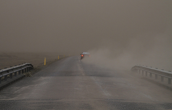 Carro passa por estrada com visibilidade mínima por cinzas lançadas pelo vulcão na cidade de Kirkjubaejarklaustur