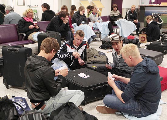 Passageiros jogam cartas enquanto aguardam no aeroporto de Edimburgo, na Escócia