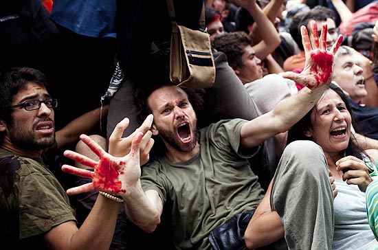 Manifestante mostra sangue de outros jovens feridos em suas mãos; repressão da polícia enfureceu espanhóis